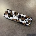 Dettaglio della fascia sportiva in maglia con motivo a mucca marrone e bianco morbido - Stampa leopardata