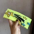 Detail of neon yellow knitted headband featuring embroidered stars and shooting stars - Neon Yellow