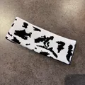 Detail of knitted cow print pattern on a white elastic headband for outdoor sports - Black Cow