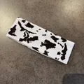 Close-up of knitted cow print headband featuring a soft black and white woven pattern - Coffee Cow