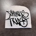 Dettaglio ravvicinato di un berretto in maglia bianca con lettere graffiti nere sulla terra - M (52-59) / Bianco