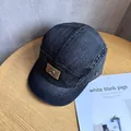 Detail of grey denim camper cap featuring brown leather patch and metal ring embellishment - Adjustable / Black