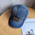 Detail of washed denim baseball cap with metal ring logo on a vintage wooden desk - Adjustable / Navy Blue