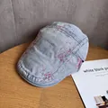 Detail einer hellblauen Denim-Schirmmütze mit rosa Farbspritzern auf einem Holztisch - M / Hellblau