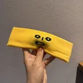 Detail of yellow knitted sports headband with minimalist cute face embroidery design - Yellow