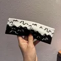 Dettaglio della fascia in maglia con motivi a onde bianchi e neri per sport e uso quotidiano - Patchwork Nero e Bianco