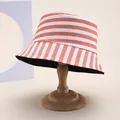 Detail of striped cotton bucket hat with orange and white patterns on a wooden stand - Orange