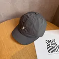Detail van een honkbalpet met korte klep en dollar-borduurwerk op houten tafel - Verstelbaar / Grijs