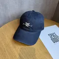 Detail of embroidered 'W' on a dark blue cotton baseball cap on a wooden surface - Adjustable / Navy Blue