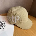 Detail of tan 5-panel camper hat featuring estp side lettering on wooden background - Adjustable / Khaki