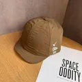 Dettaglio cappellino marrone con visiera corta e logo su superficie di legno - Regolabile / caffè