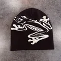 Dettaglio di un berretto nero con il motivo a rana bianca lavorata a maglia sul tessuto - M (52-58cm) / Caffè