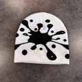 Dettaglio del berretto in maglia bianco con schizzi di inchiostro nero e trama morbida - M (52-58cm) / Bianco