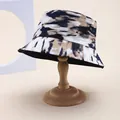 Detailed view of tie-dye bucket hat with abstract ink pattern on vintage wooden stand - M (55-58cm) / Black