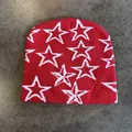 Gedetailleerde gebreide textuur van rode muts met witte jacquard sterren op steen - M / Rood Met Witte Sterren