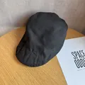 Détail d'une casquette plate noire minimaliste sur une surface en bois rustique - M / Noir