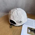 Dettaglio del cappellino beige in ripstop con coulisse regolabile e ricamo laterale - Regolabile / Bianco