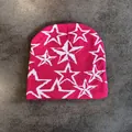 Gedetailleerde close-up van de felroze gebreide textuur en het witte sterpatroon van de muts - M / Roze Met Witte Sterren
