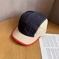 Close-up of a 5-panel outdoor cap with color-block navy and beige fabric on a wooden table - Navy Blue