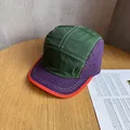 Detailed view of color-block 5-panel camp cap with green fabric and orange trim - Green