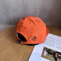 Dettaglio del cappellino da trekking arancione con coulisse e ricamo montagna - Regolabile / Rosso Arancio