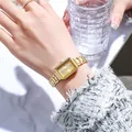 Detail of elegant gold square quartz watch with metal strap on model holding a glass - Gold