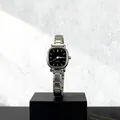 Dettaglio di orologio al quarzo quadrato con cinturino in metallo argento su base - Indici Nero