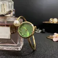 Détails d'une montre bracelet dorée élégante avec cadran vert et perle nacrée - Vert