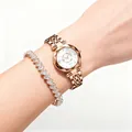 Detail view of rose gold quartz watch and sparkling heart bracelet set on wrist - White + Bracelet