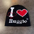 Detail van zwarte gebreide muts met witte 'I HUGGLE' tekst en rood hartjespatroon - M / Zwart