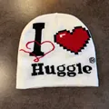 Detail van de gebreide textuur en 'I Huggle' hartborduurwerk op een witte muts - M / Wit