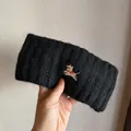 Macro view of plush knit fabric and embroidered puppy detail on the black winter headband - Black