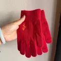 Detail von roten Strickhandschuhen mit goldener Stickerei und Touchscreen-Öffnung - Großes Glück