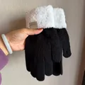 Nahaufnahme von Strickhandschuhen mit weißen Lammwollbündchen und Leder-Zierpatch - Schwarz