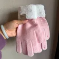 Detail von rosa Strickhandschuhen mit weichen weißen Pelzmanschetten und Lederetikett - Rosa