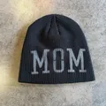 Nahaufnahme der schwarzen Strickmütze mit MOM-Schriftzug auf einer Texturoberfläche - M (54-58cm) / Schwarz