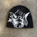 Detail van de zwarte gebreide muts met wit engelenpatroon op grijze stenen achtergrond - M (54-60cm) / Zwart