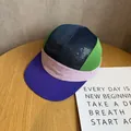 Top view of multi-color five-panel camp hat with breathable mesh and flat brim on wood table - Adjustable / Purple Green Patchwork
