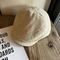 Detailed close-up of beige linen cotton flat cap on rustic wooden tabletop with card - M (56-58cm) / Beige