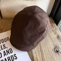 Detail view of dark brown linen-cotton flat cap with textured fabric on a wooden table - M (56-58cm) / Coffee