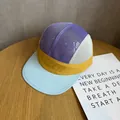 Close-up of a colorful 5-panel mesh flat brim hat with breathable purple and yellow fabrics - Adjustable / Blue & Yellow Patchwork