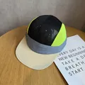 Close-up of five-panel mesh cap showing breathable black and neon yellow textures - Adjustable / Beige and Navy Patchwork