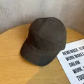 Detail van een houtskoolgrijze 5-panel katoenen baseballcap op houten achtergrond - Verstelbaar / koffiekleur
