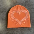 Detail shot of orange knit beanie featuring a white pixelated heart pattern and fine stitching - M (52-59) / Orange