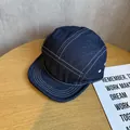 Détail d'une casquette camper en denim bleu foncé avec surpiqûres blanches et œillets - Réglable / Bleu foncé