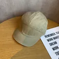 Detail van een kaki 5-panel pet met korte klep op een houten tafel met decoratieve prop - Verstelbaar / Khaki
