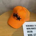 Detailed macro view of orange trucker hat with black stars and breathable mesh texture - Adjustable / Orange