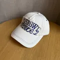 Dettaglio del ricamo blu con bordi sfrangiati su un cappellino da baseball in cotone bianco - Regolabile / Bianco