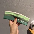 Dettaglio della fascia in maglia a righe verdi con ricamo Hope per sport e fitness - Verde