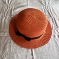 Detail eines hellorangen Strohhuts mit einer schicken schwarzen Schleife aus Satin - Orangerot
